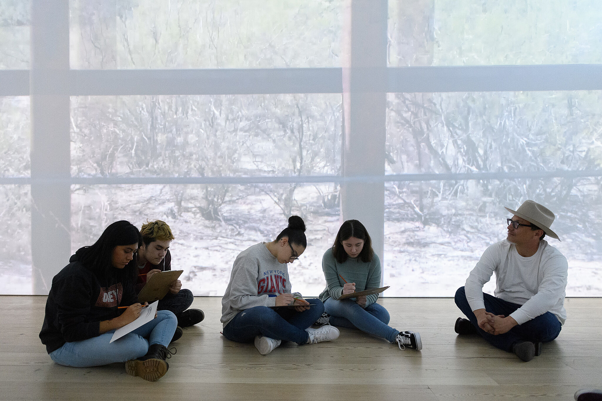 Postcommodity member Kade L. Twist leads a sketching activity in their installation.