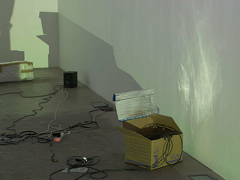 Installation view of Trisha Baga Plymouth Rock exhibition. Depicts a box with several wires inside and on the ground.