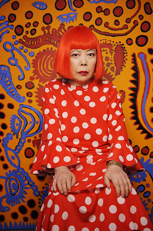 Woman in red and white dot dress in front of painting.