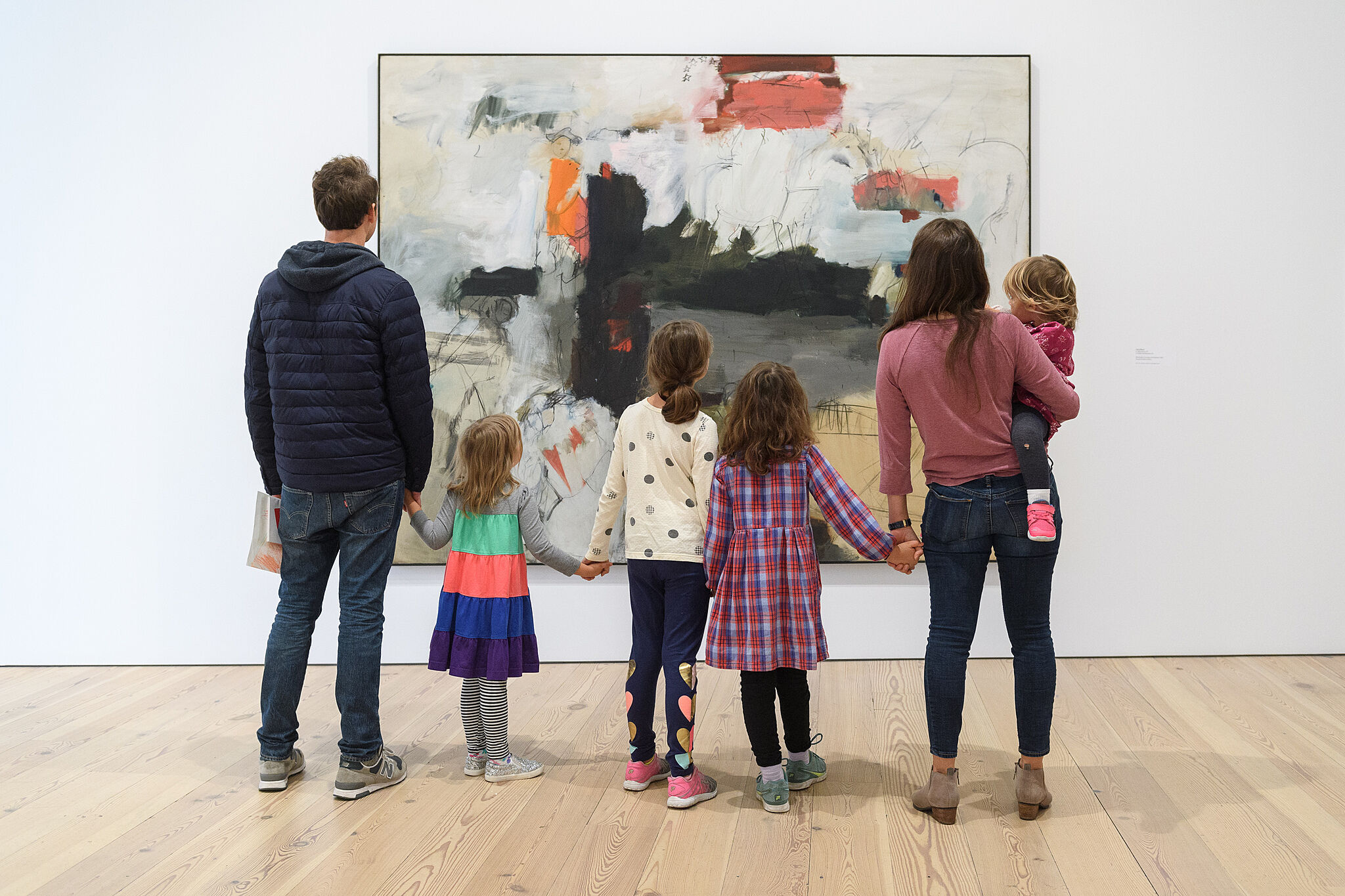 A family holding hands and looking at art.