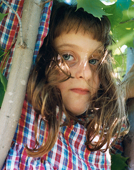 Girl hanging from a tree branch.