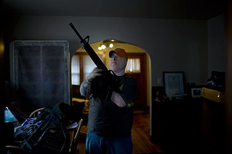 A photograph of a man holding a gun. 