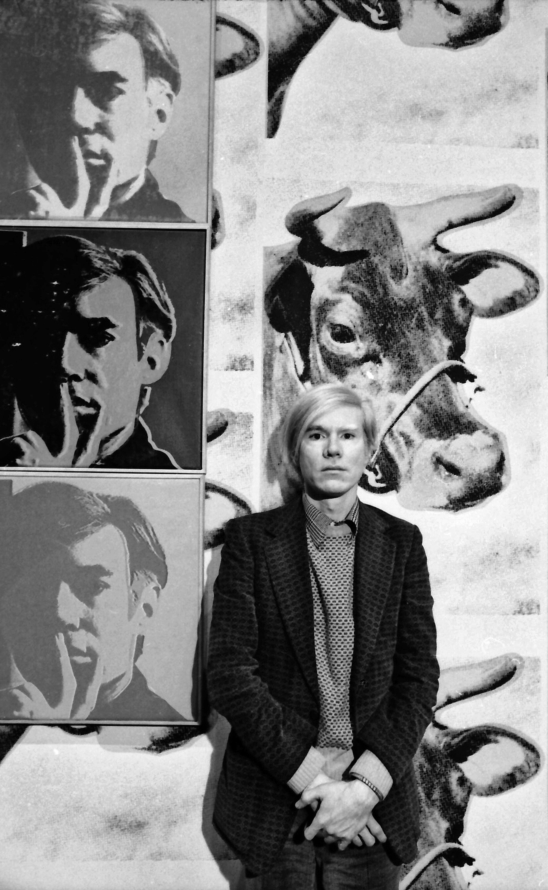 Andy Warhol sitting in front of his work.