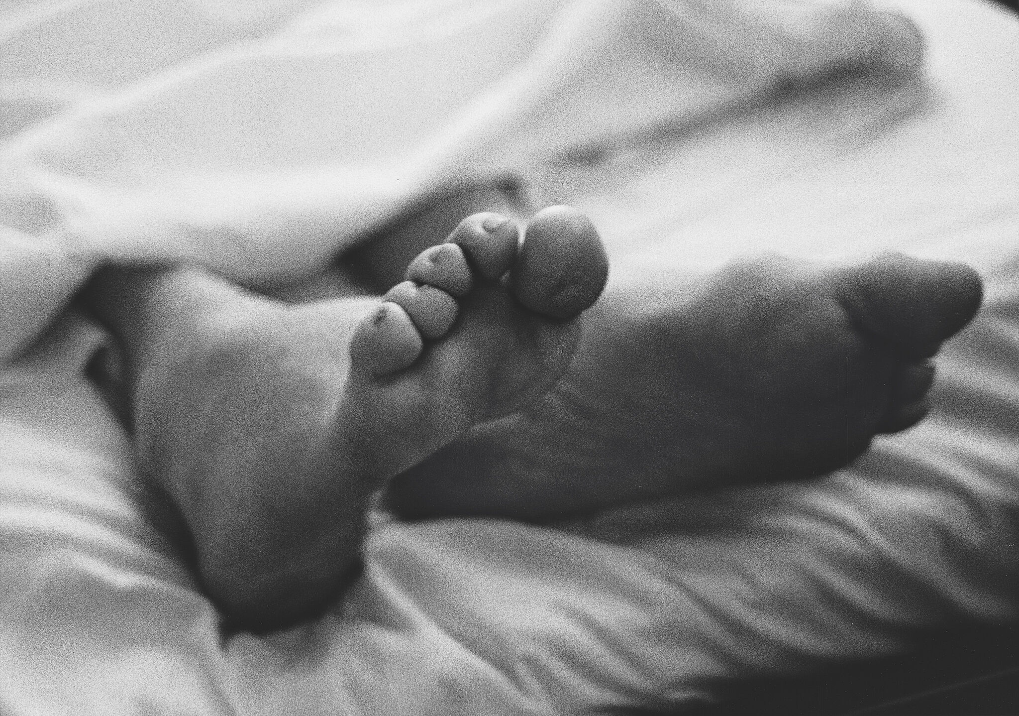 Photograph of feet on a bed in black and white. 