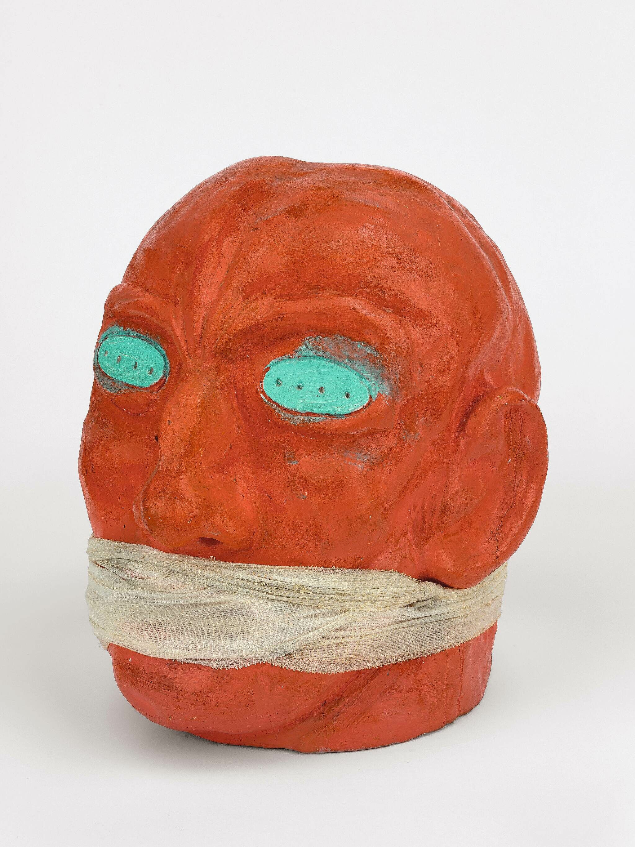 Head painted red with bandage around mouth.