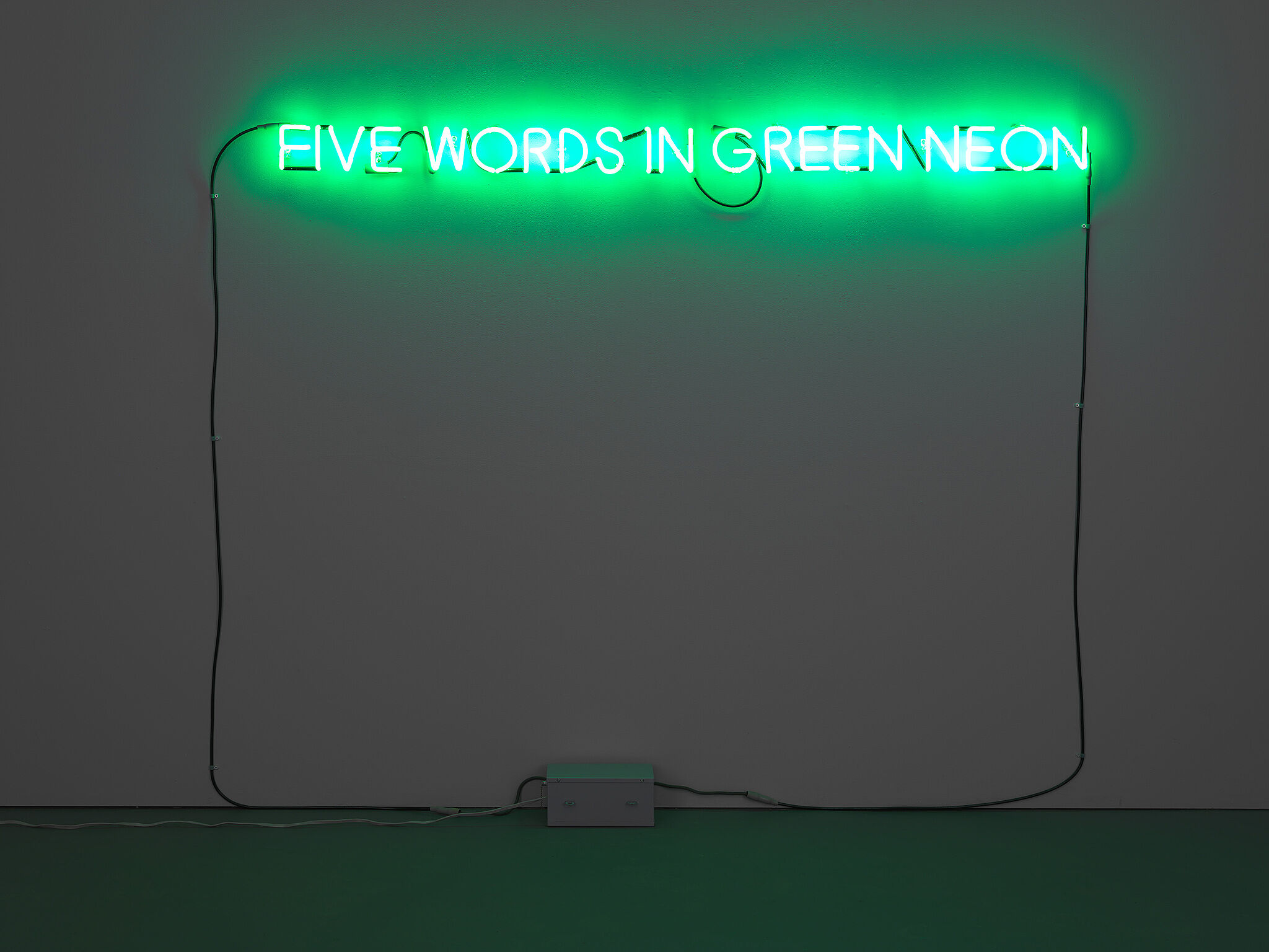 Five words in green neon lights hanging on the wall.