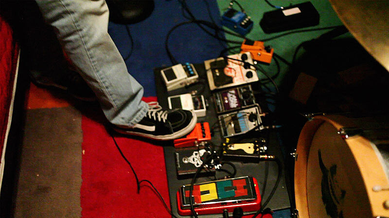 A person is playing different electronic music pedals. 