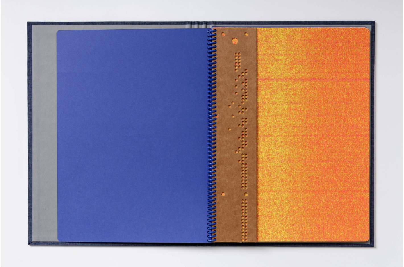 A book with a blue page on the left and an orange page on the right with perforated circles.