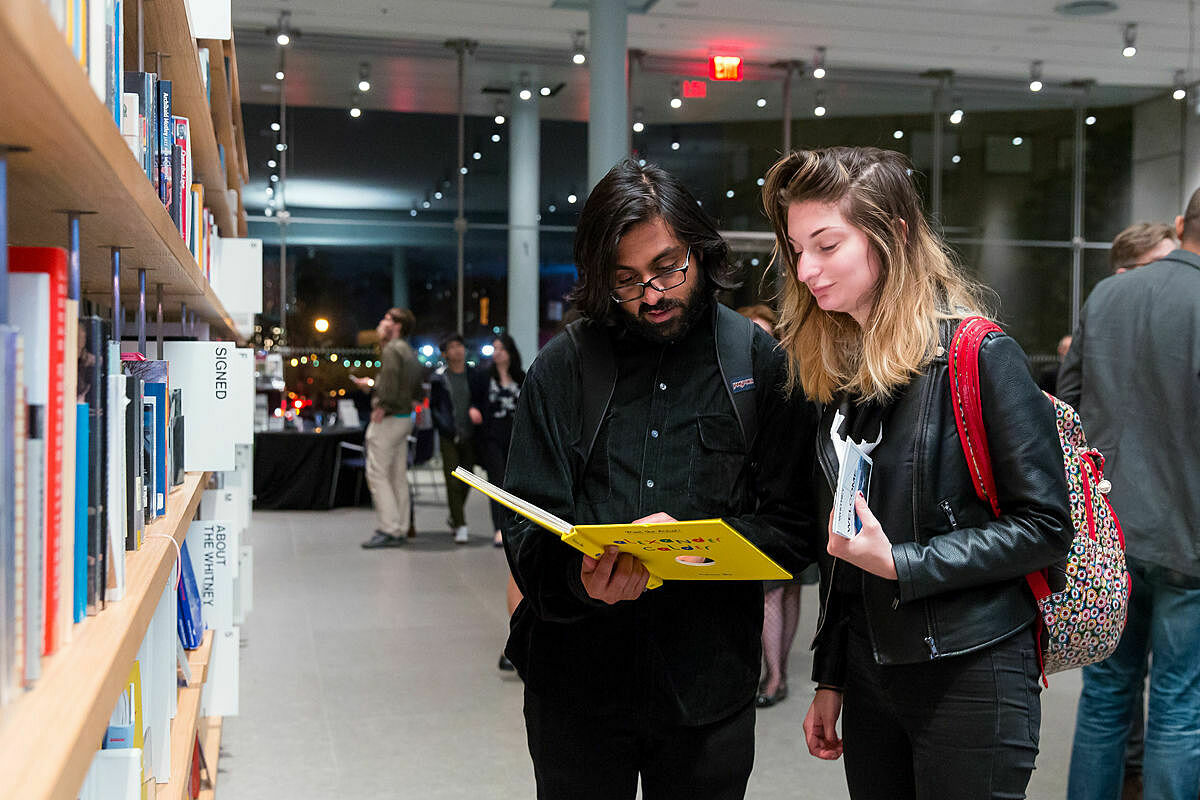 Two visitors look at a book in the Whitney shop