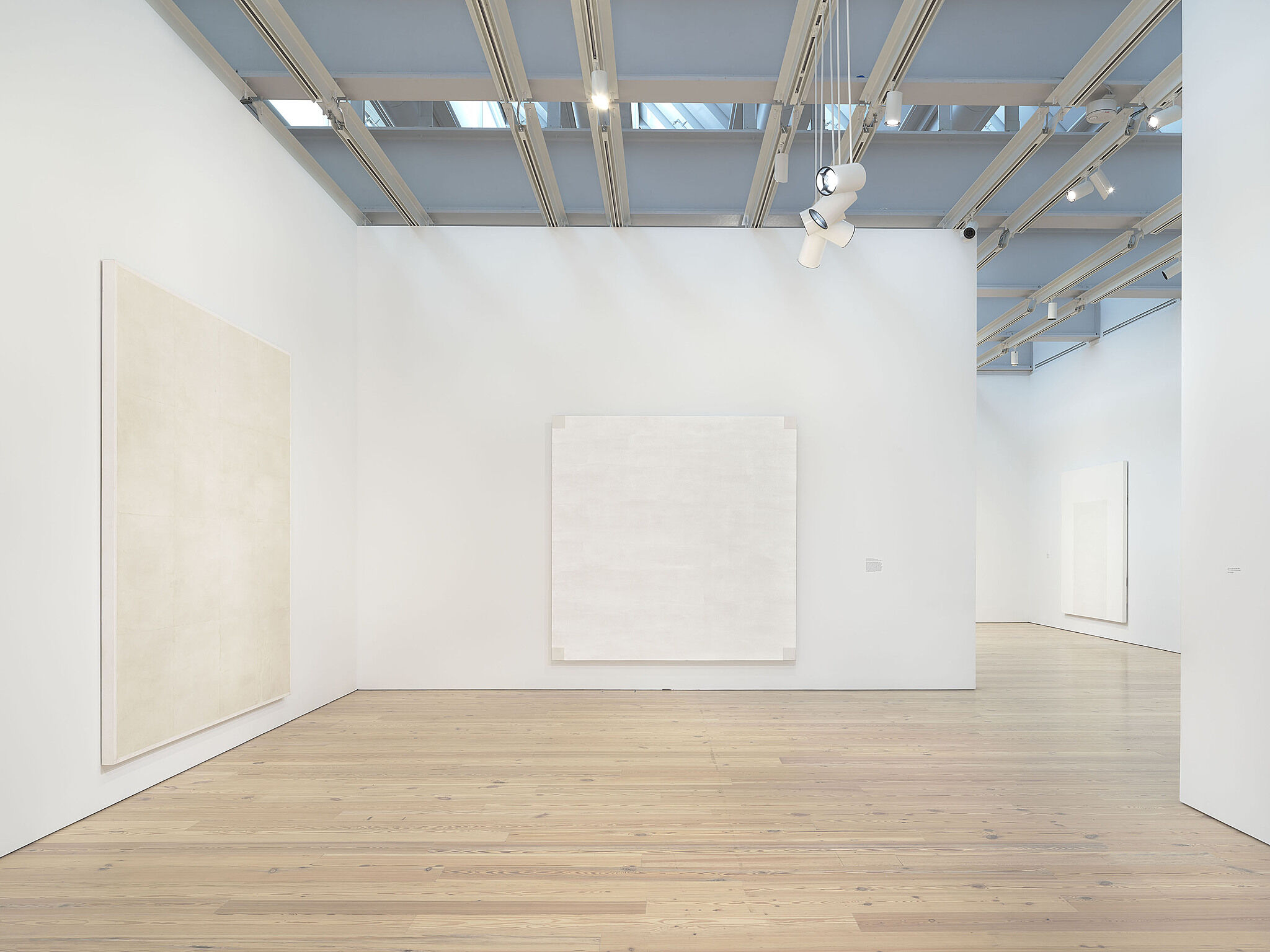 Installation view of Mary Corse: A Survey in Light, including Untitled (White Grid, Horizontal Strokes), 1969; Untitled (Light Painting), 1971; Untitled (White Arch Inner Band Series), 1996
