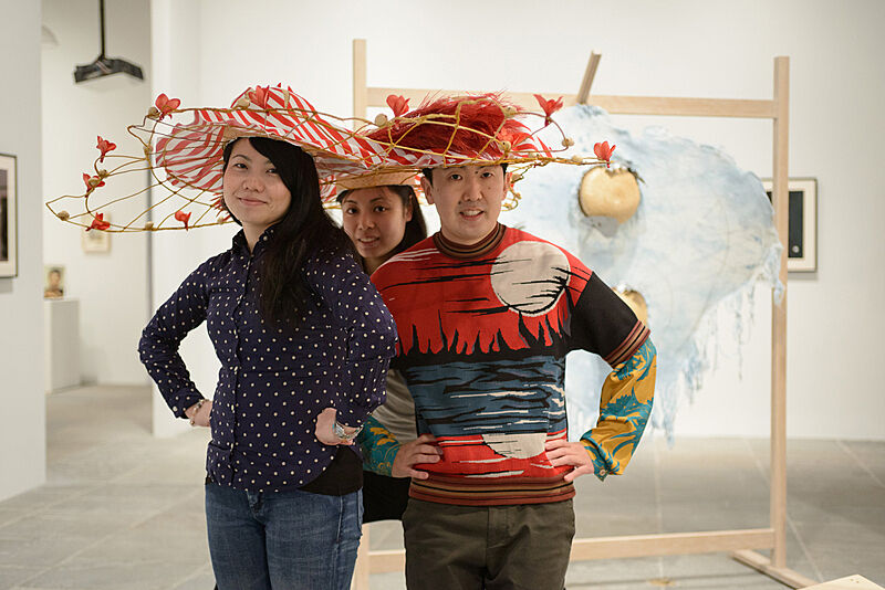 Three people wearing flower decorated hats. 