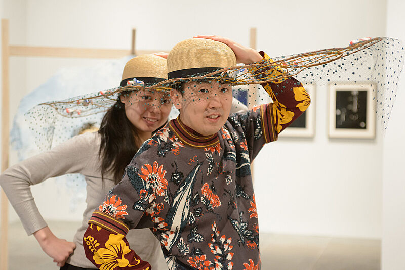 Two people wearing decorated hats. 