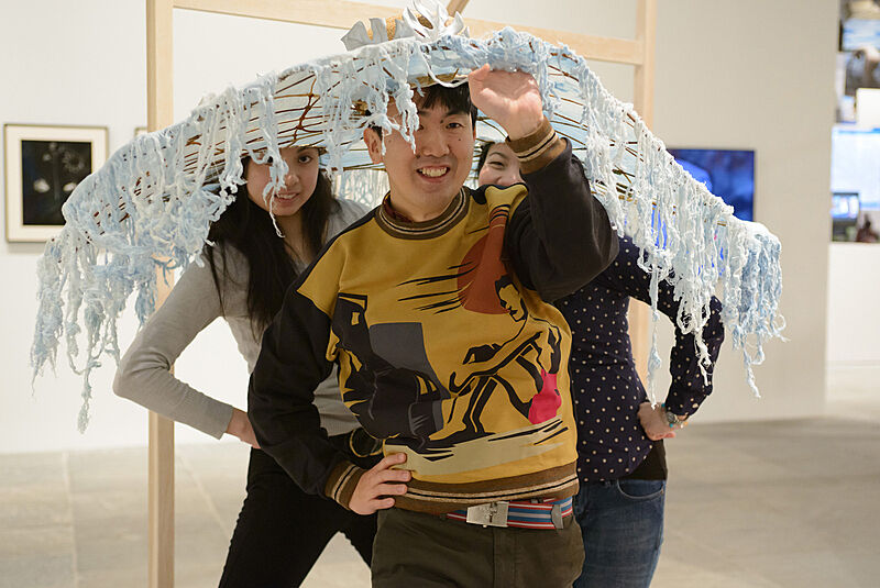 Three people wearing decorated hats. 