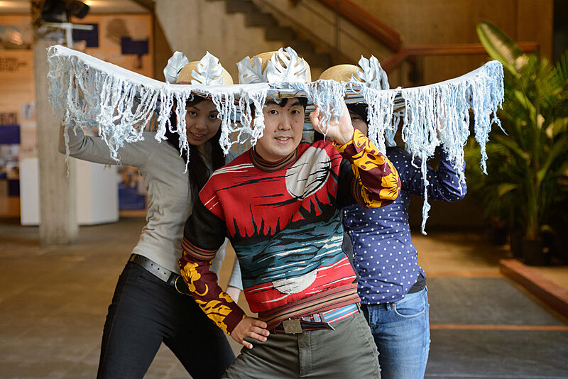 Three people wearing decorated hats. 