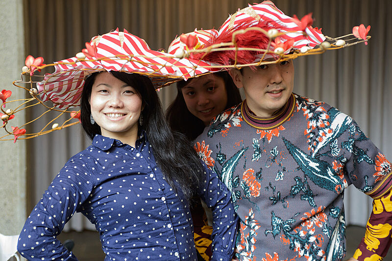 Three people wearing decorated hats. 