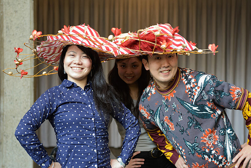 Three people wearing flower decorated hats. 