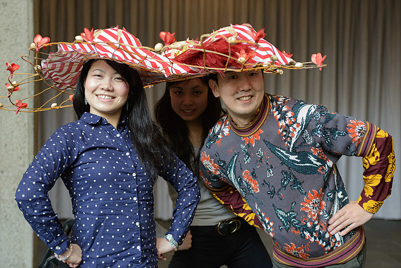Three people wearing decorated hats. 