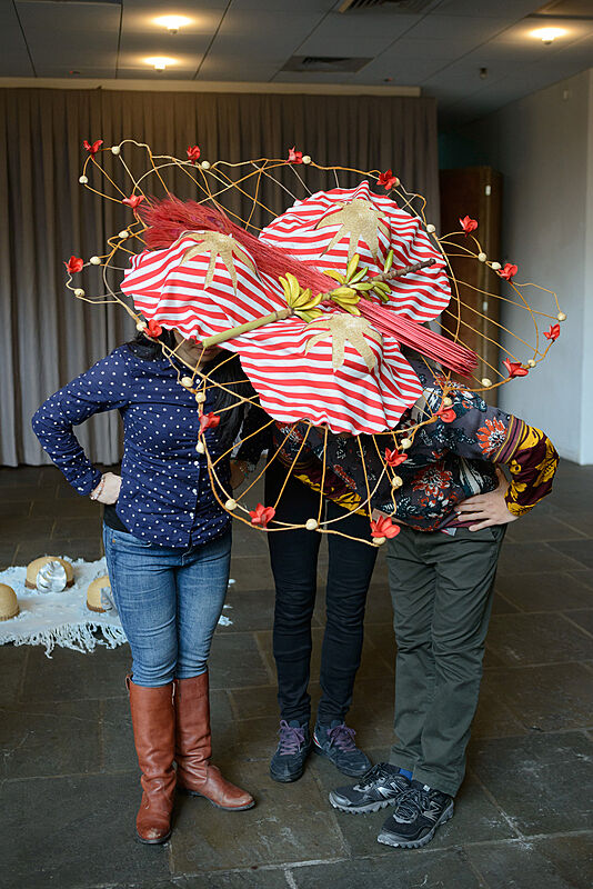 Three people wearing decorated hats. 