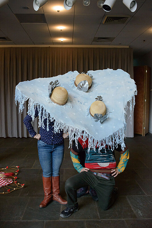 Three people wearing decorated hats. 