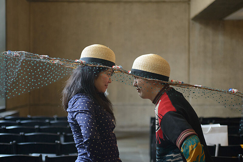 Two people wearing decorated hats. 