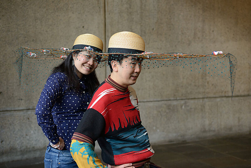 Two people wearing decorated hats. 