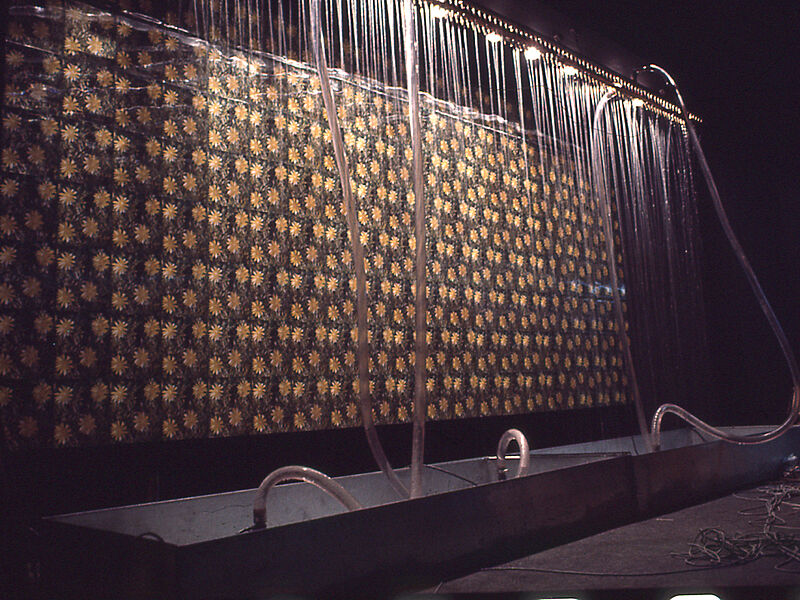 A water-spray system in front of a big print of daisies. 