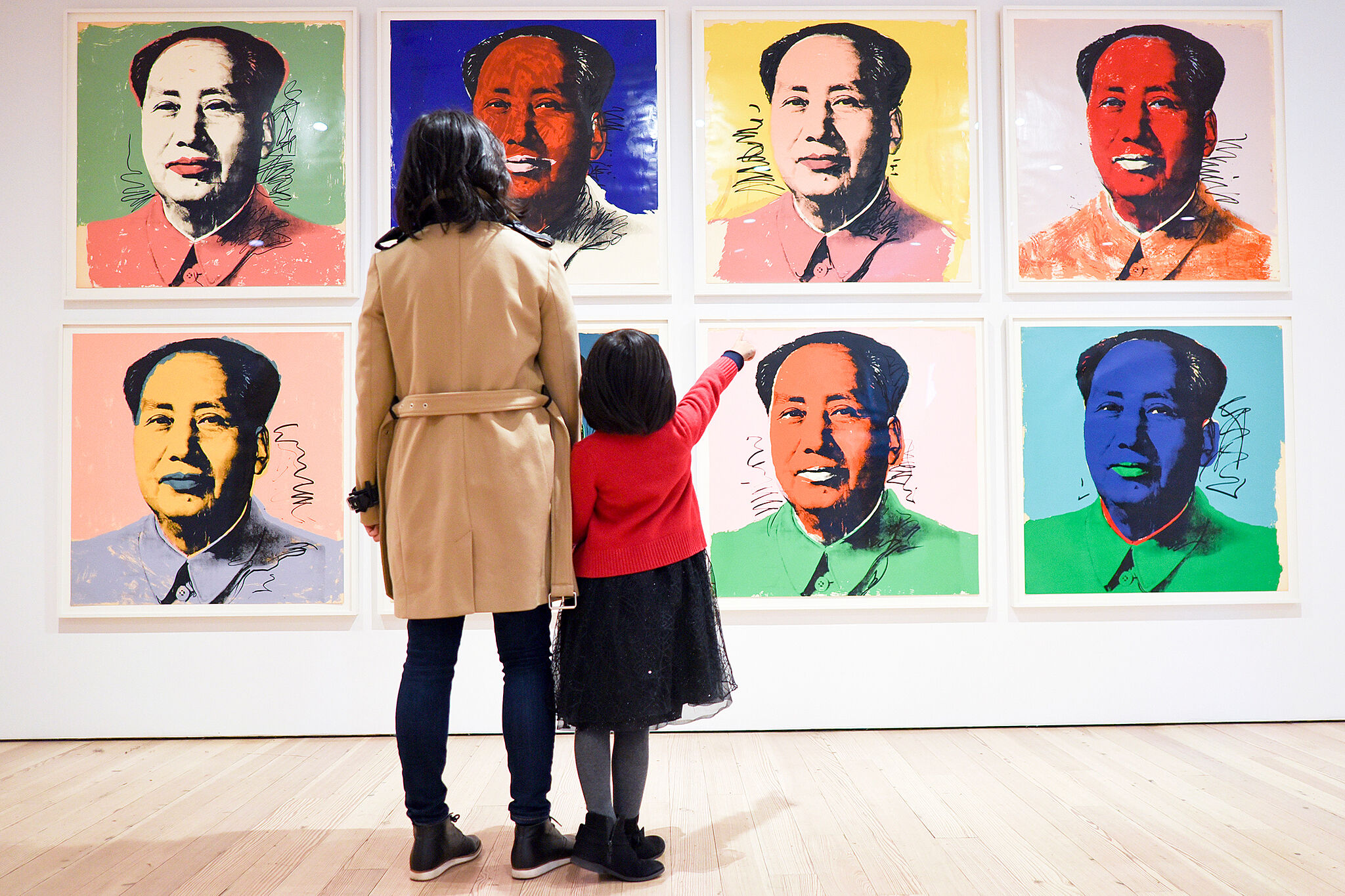A parent and child look at Warhol's Mao paintings