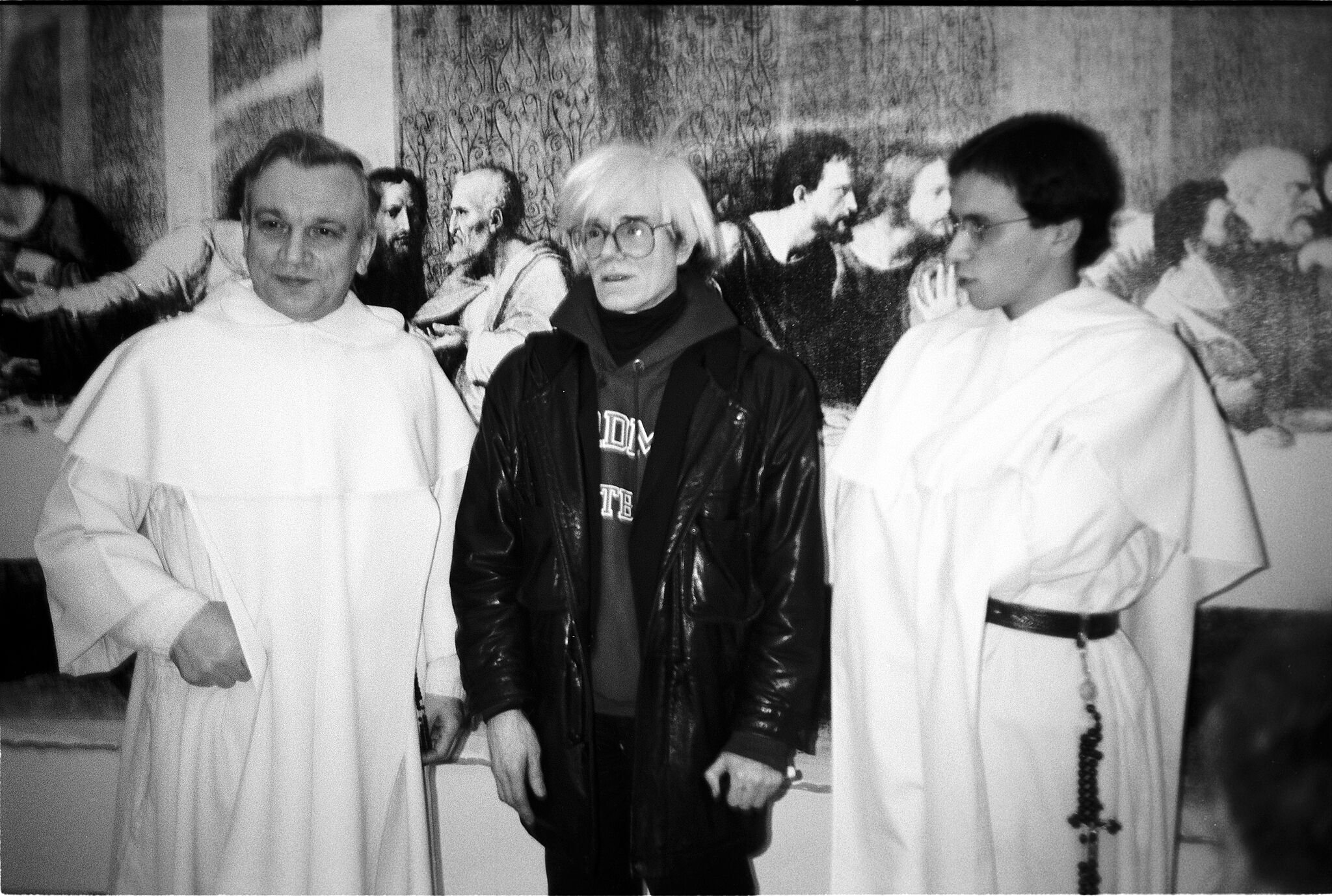 Andy Warhol standing in front of priests in Milan.