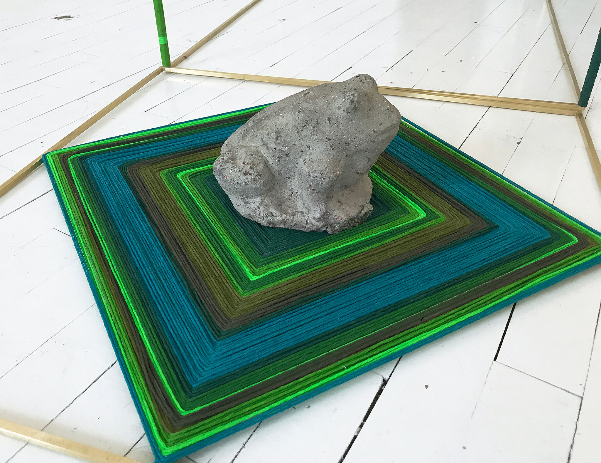 a frog sculpture sitting on a colorful square