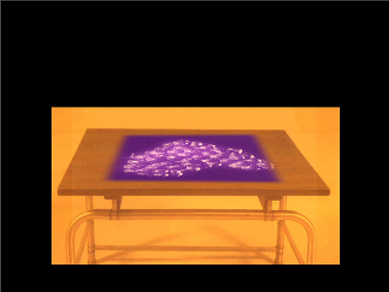 A photograph of a table with purple projection on the surface. 