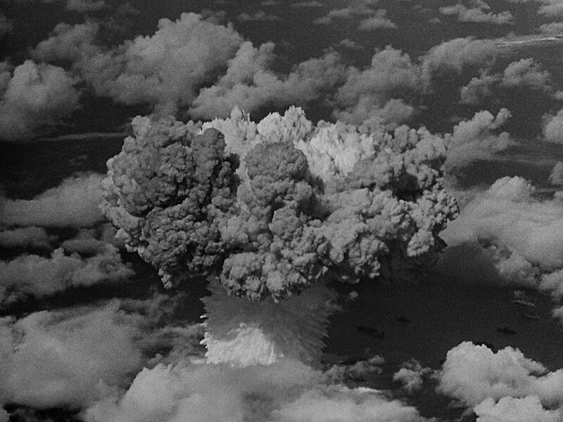 Black and white photo of the expanding cloud of a nuclear explosion, seen from the air.