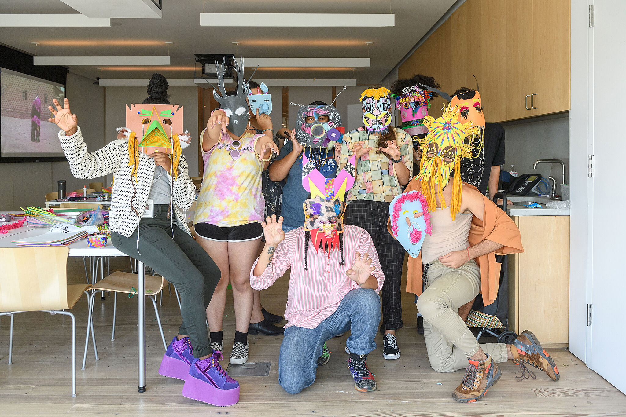 A group of nine people pose for a group photo, wearing handmade paper masks