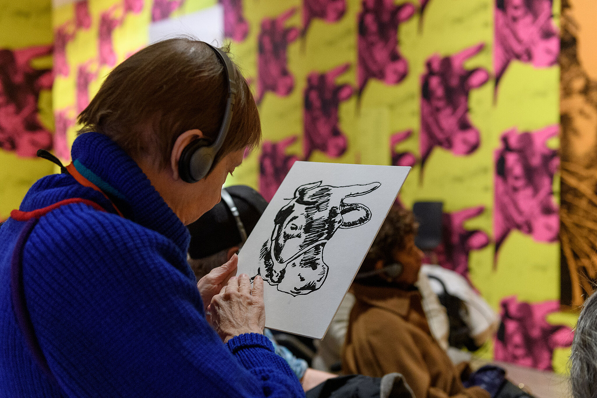 A visitor uses headphones and a touch object to explore a gallery.