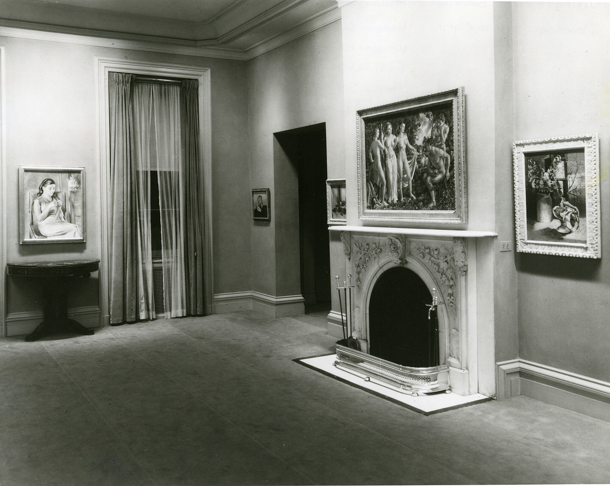 Several paintings hang on wall in a room with a fireplace