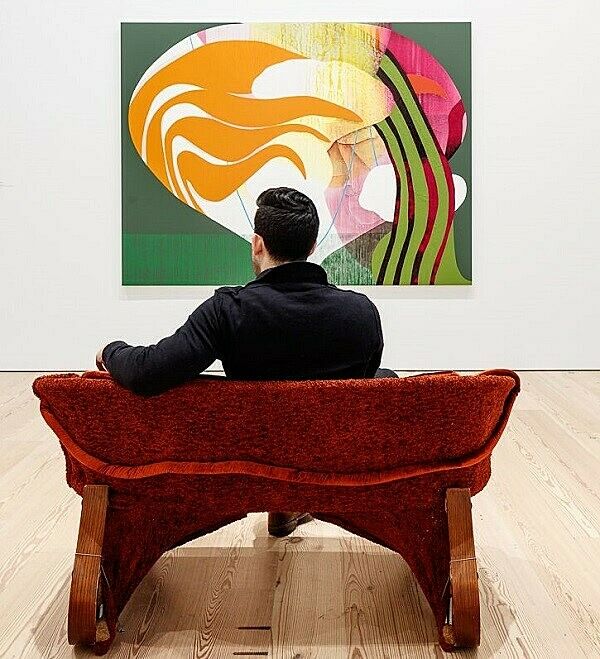 A person sitting on a couch in a gallery.