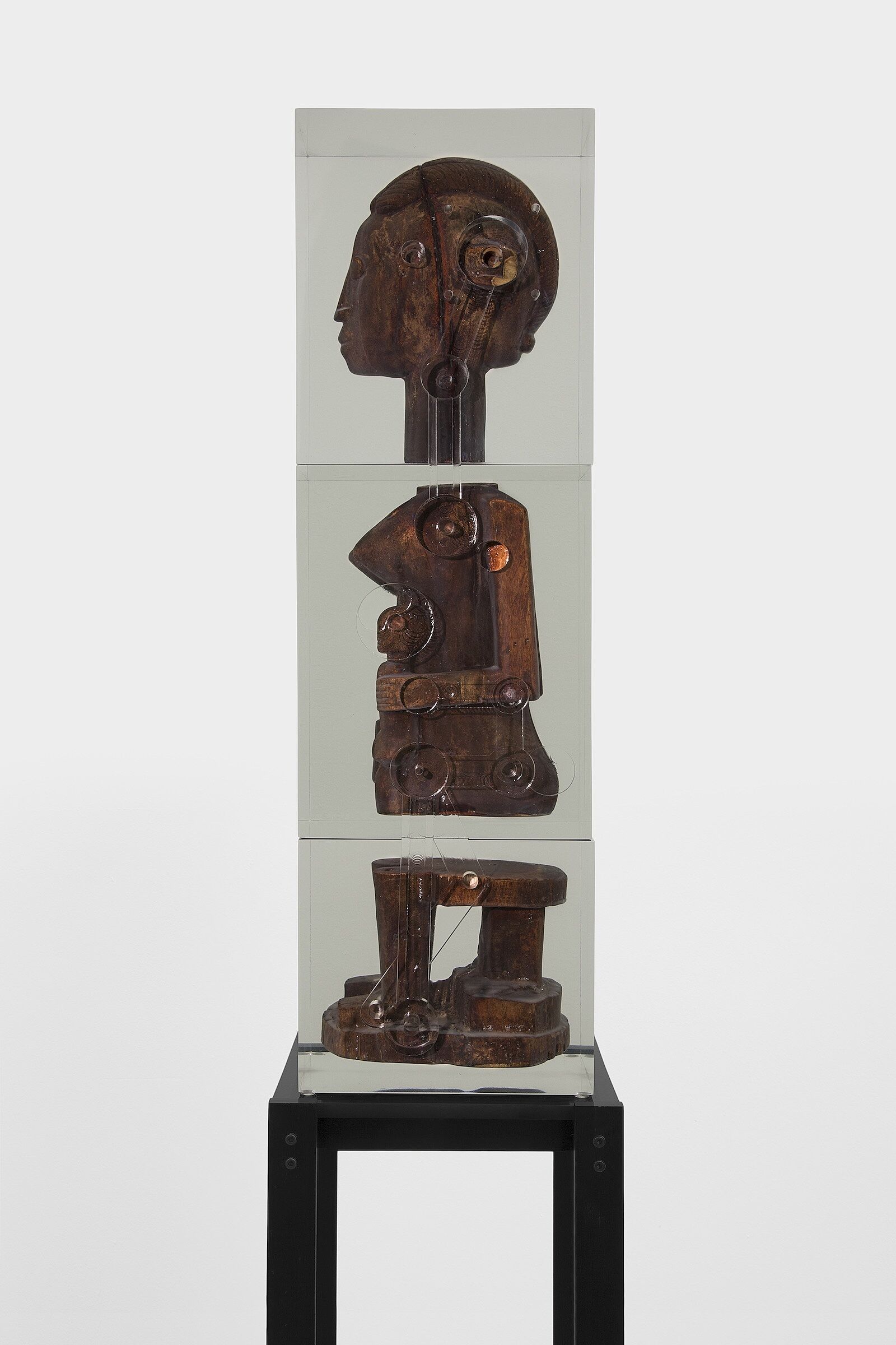 A wooden sculpture of a female figure cast in a block of resin.