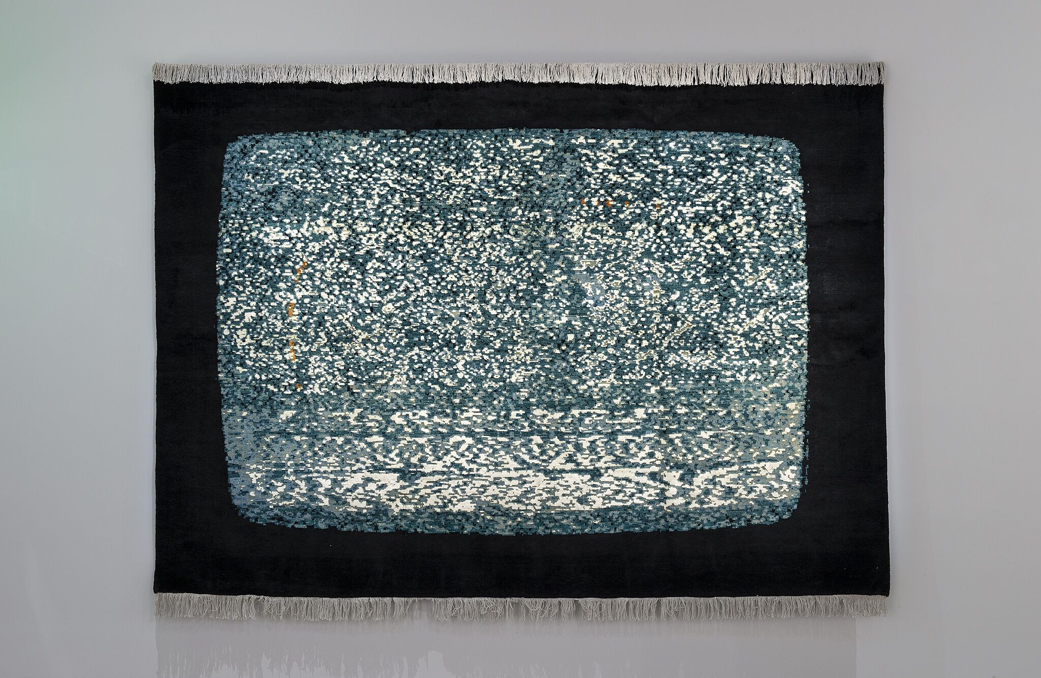 A textile hanging on a wall with the look of a television tuned to a dead channel.