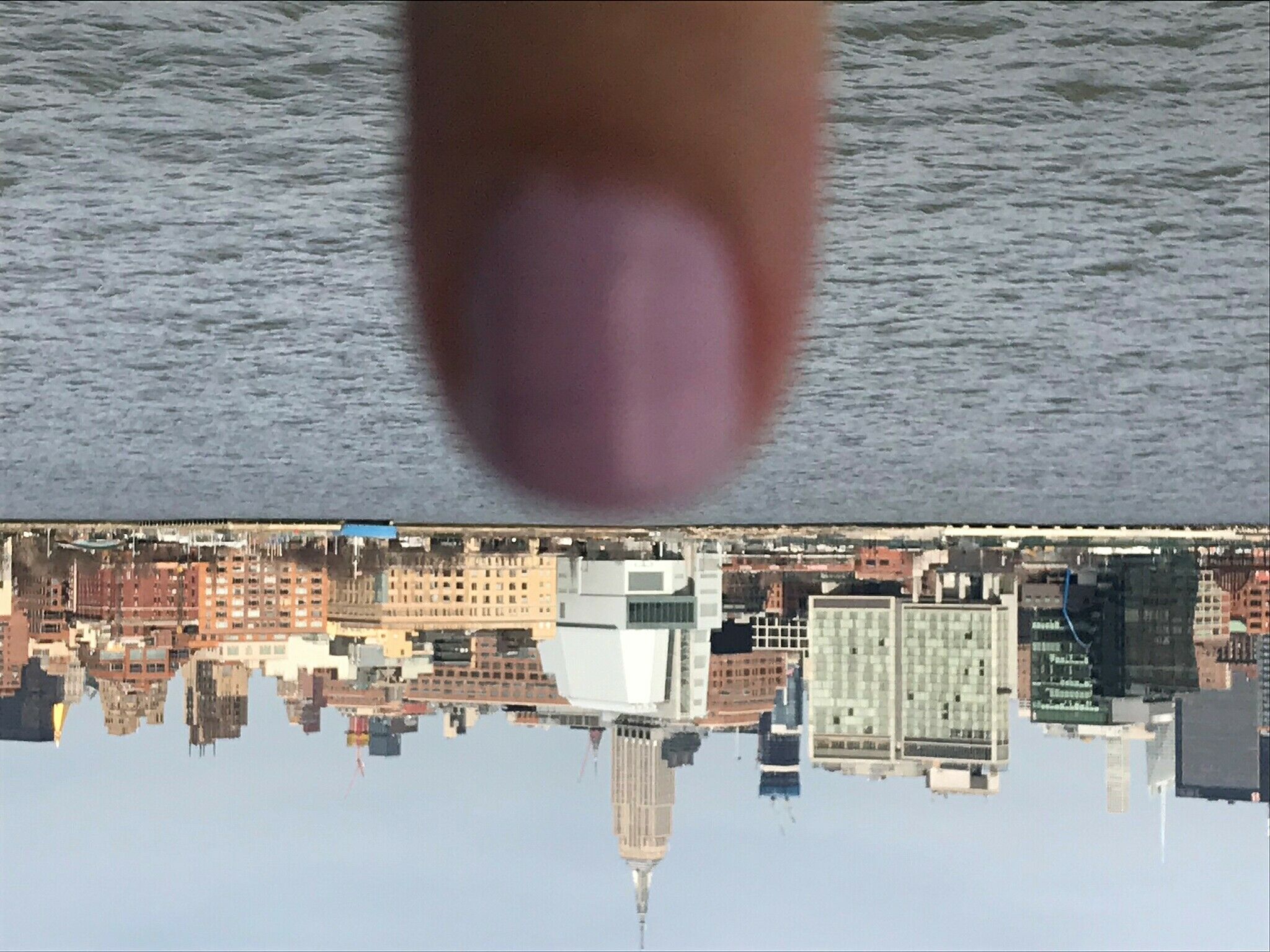 The New York City skyline with a close-up image of a finger in front.