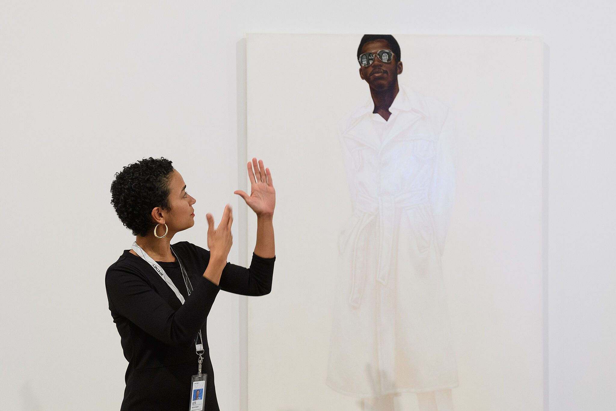 A photograph of a person signing in front of an artwork.