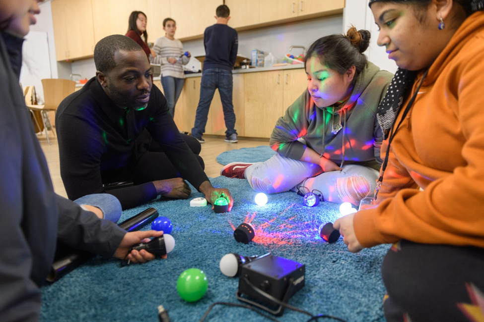 A photograph of an artist working with youth.