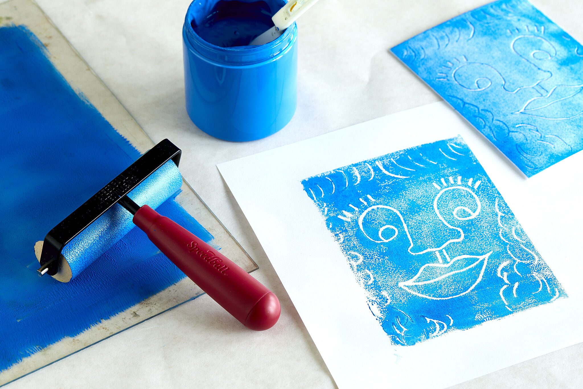Art tool on a table such as paint, rollers, and paper.