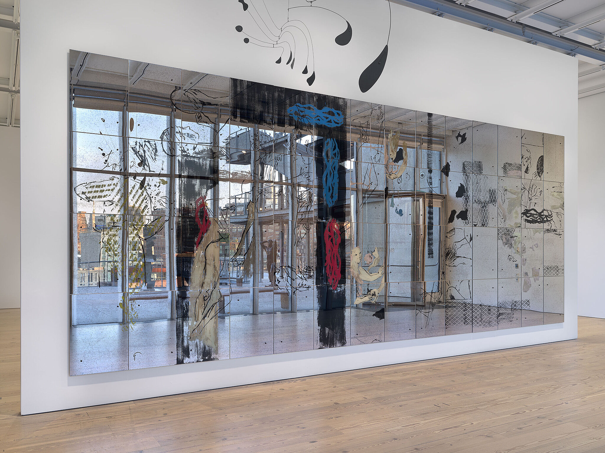 An image of the Whitney galleries with a large wall piece and hanging sculpture