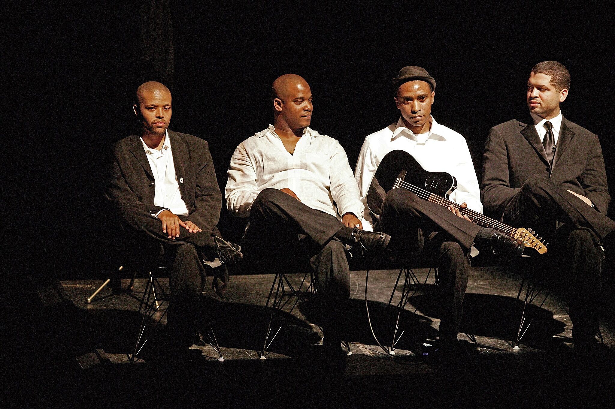 Four men sitting on a stage.