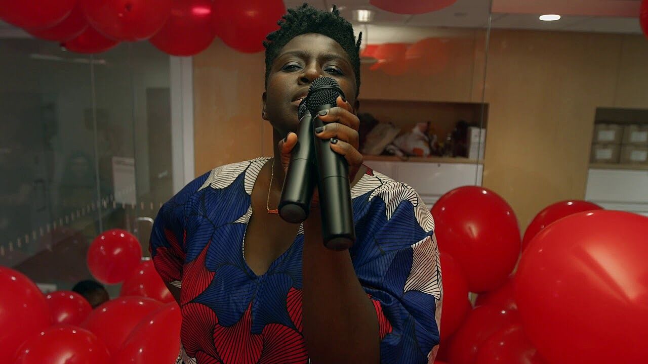 A person holding two microphones surrounded by red balloons