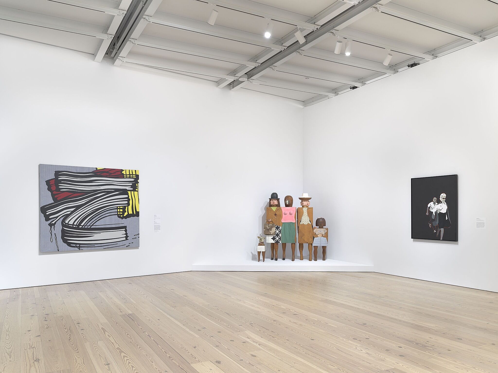 An image of the Whitney galleries with a standing sculpture and two wall artworks