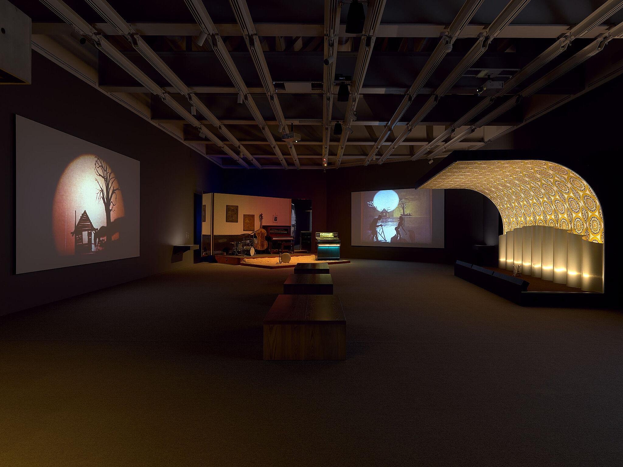 An image of the Whitney galleries with various video projections, stages, and musical instruments