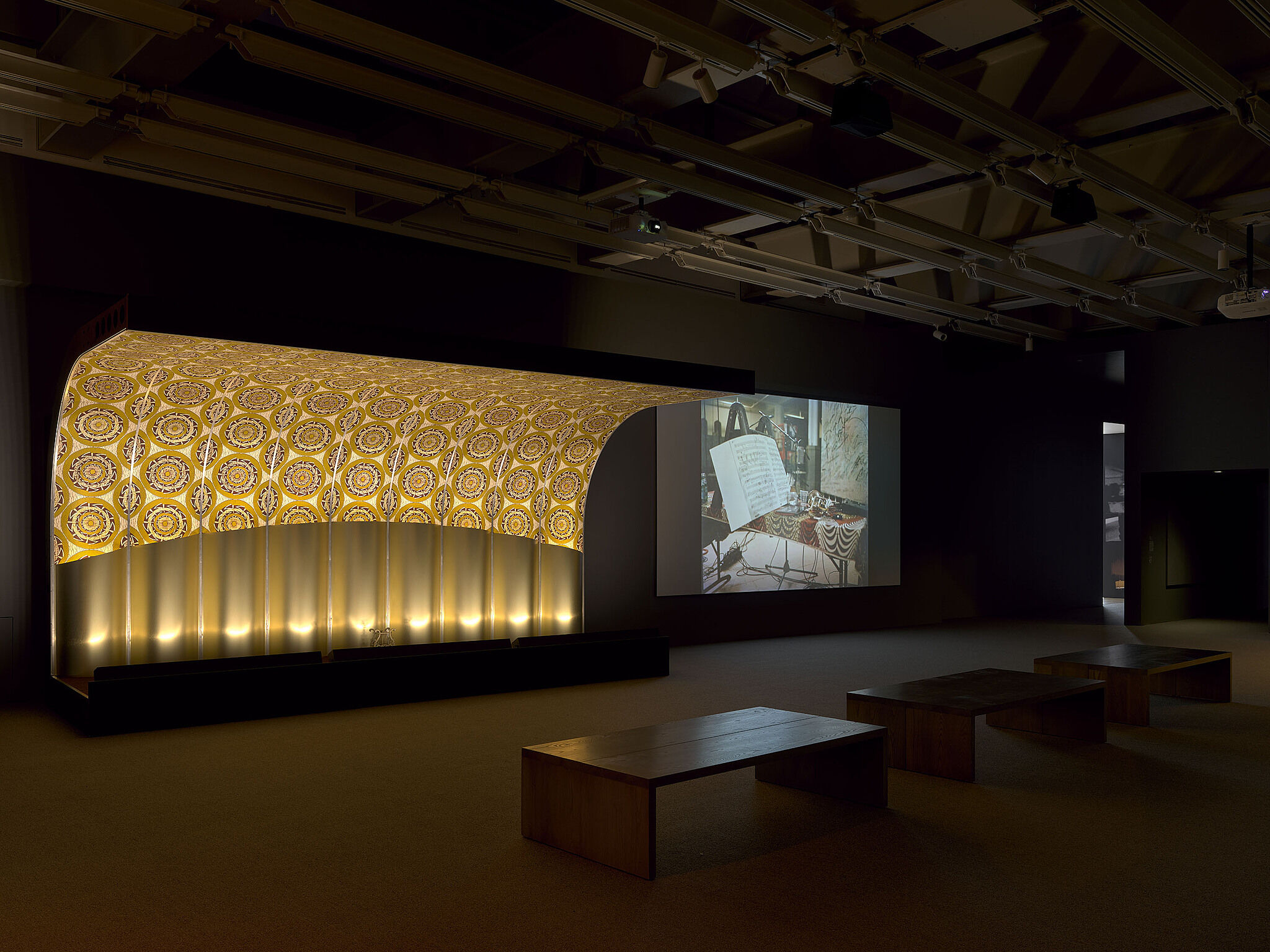 An image of the Whitney galleries with various video projections, stages, and musical instruments