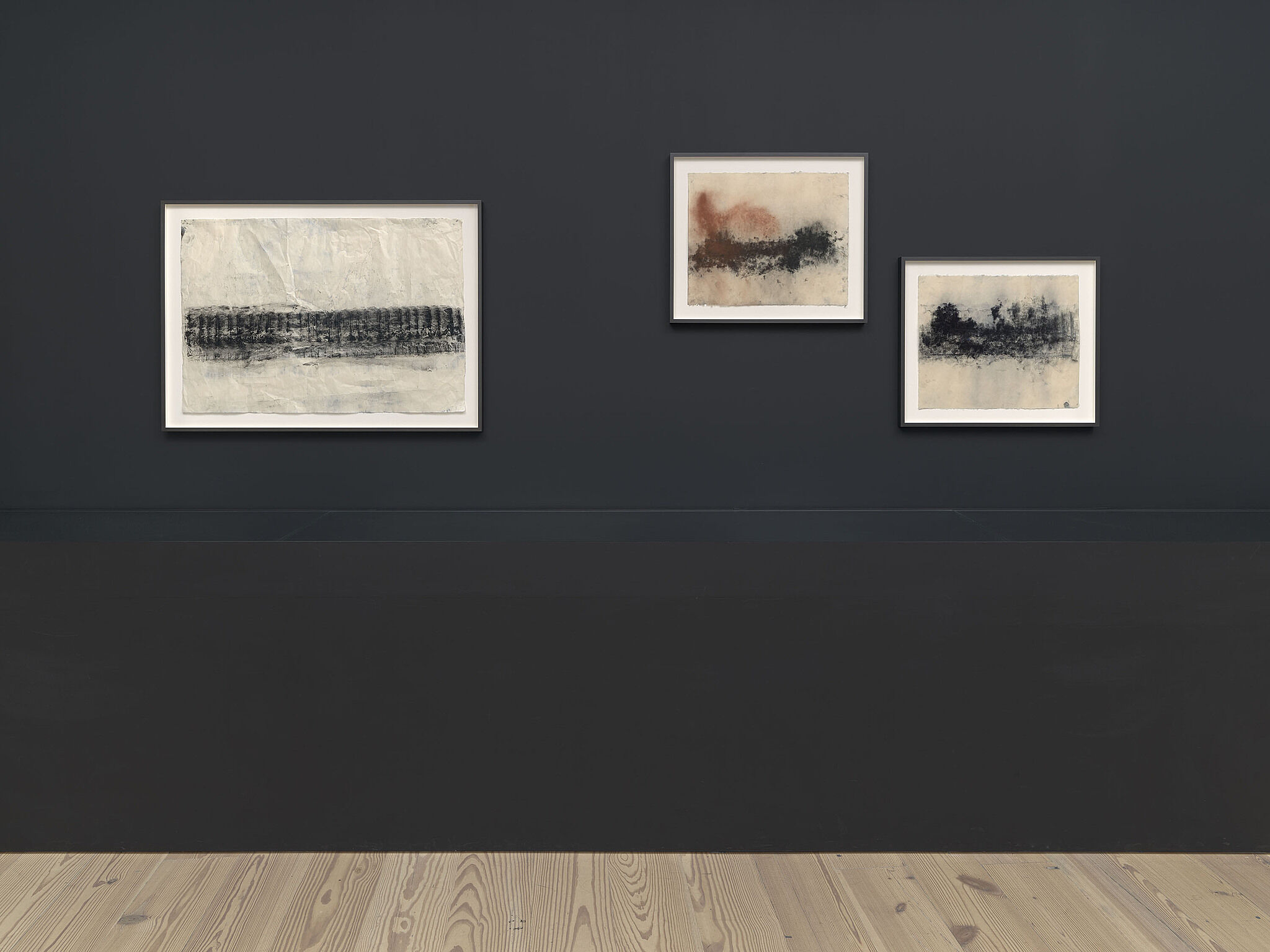 A wall of various charcoal drawings