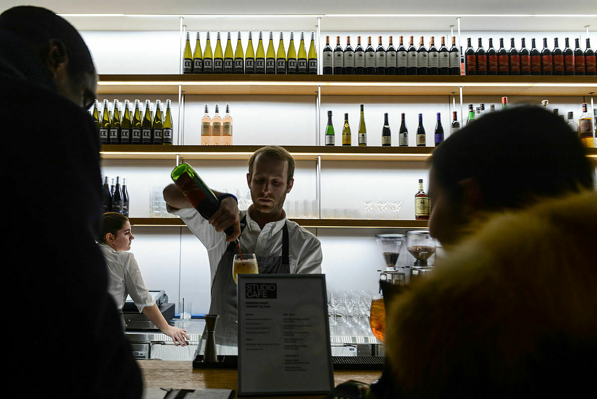 A man pours a glass in front of a bar.