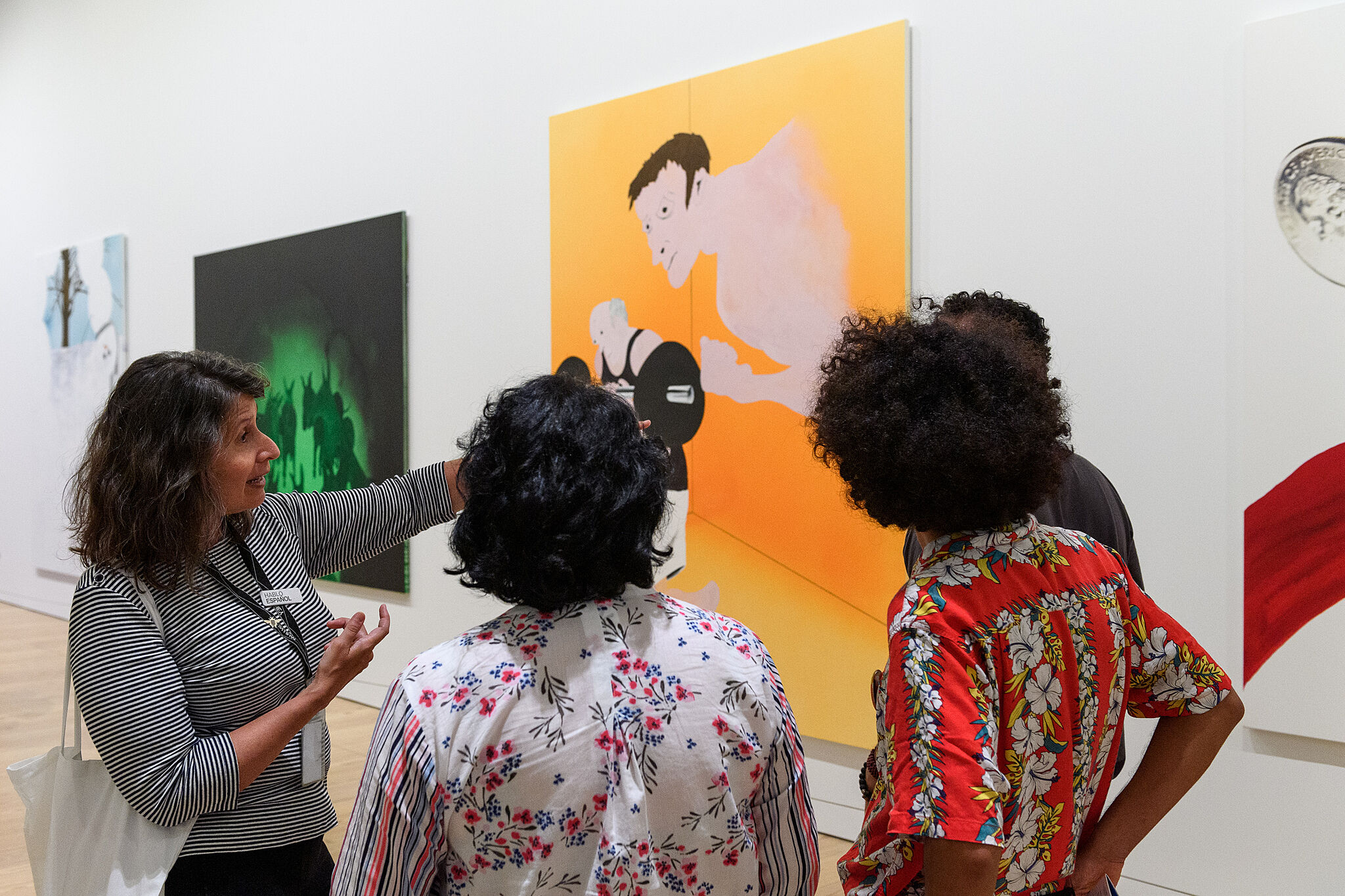 Four individuals stand around a painting speaking and pointing.